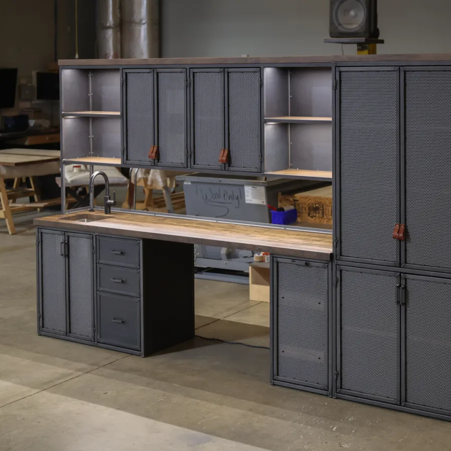 Modern industrial-style workstation with black metal cabinets and wooden countertop in workshop.