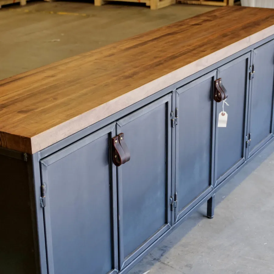 Industrial style cabinet with black metal doors and a thick wooden top standing on concrete floor