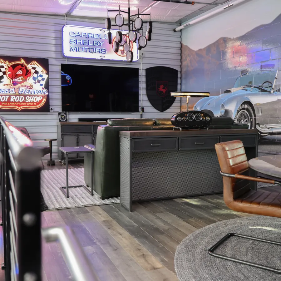 Modern automotive-themed lounge with leather chairs, large TV, car mural, and neon Shelby Motors signs