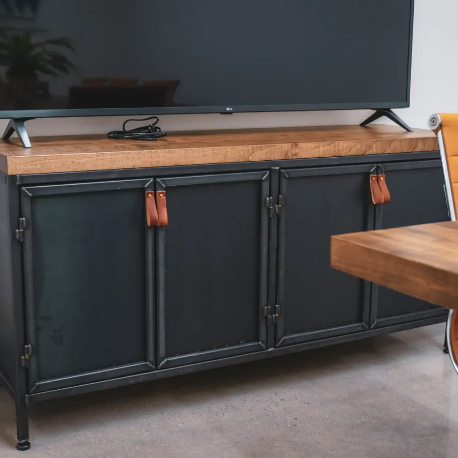 Modern living room with a black metal TV cabinet, wooden top, flat screen TV, and orange office chair.