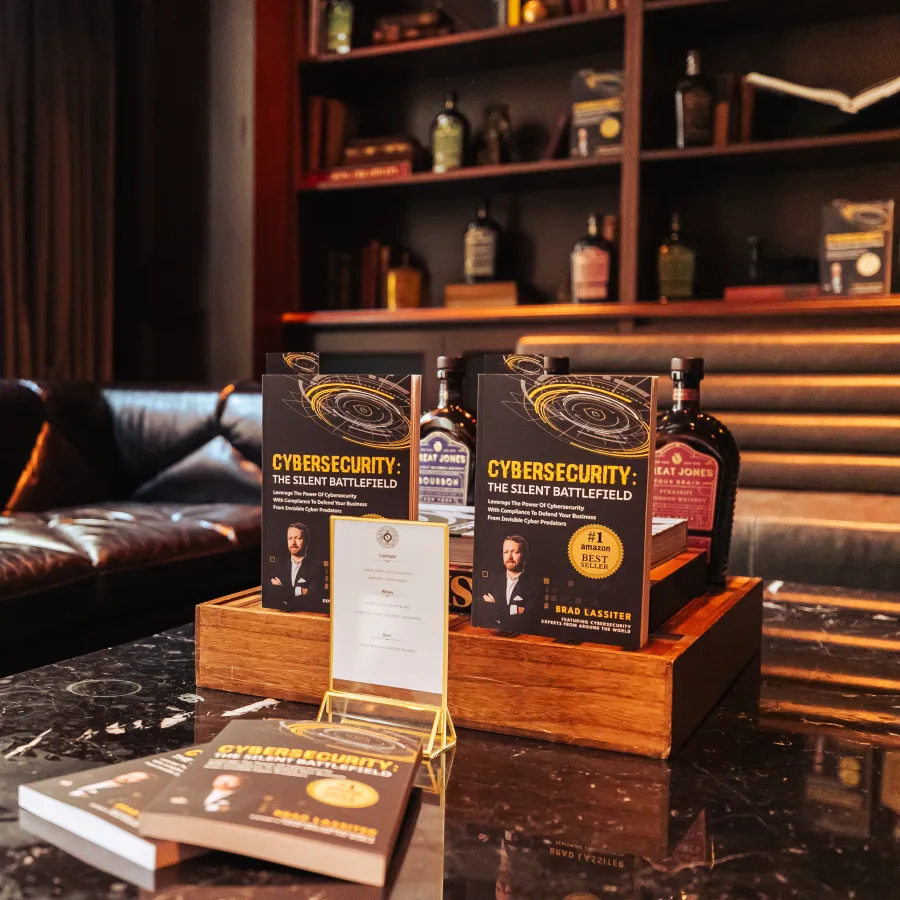 Books titled Cybersecurity The Silent Battlefield displayed on a table with leather couches and shelves in background