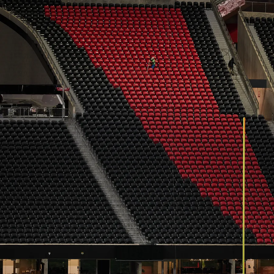 Red and black stadium seats with one person seated, featuring an Atlanta Falcons logo near the field goal post.