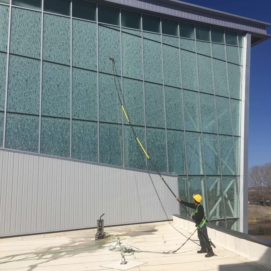 a person holding a broom and a bird in front of a glass building