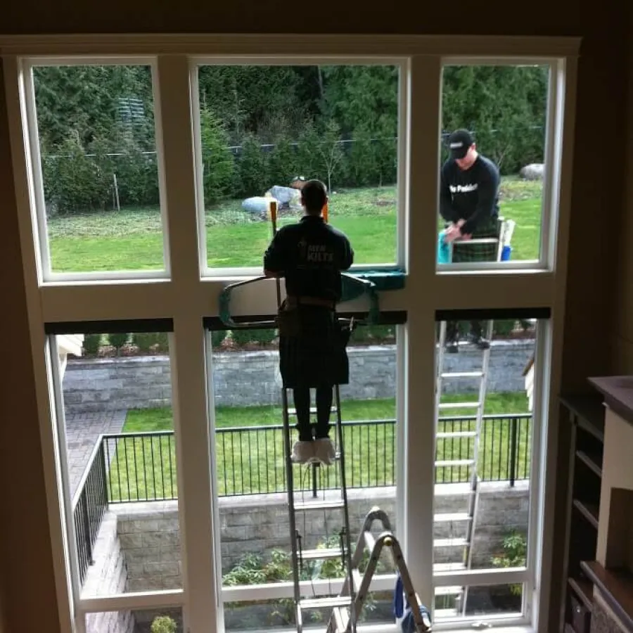 a couple of men standing in a room with windows and a railing