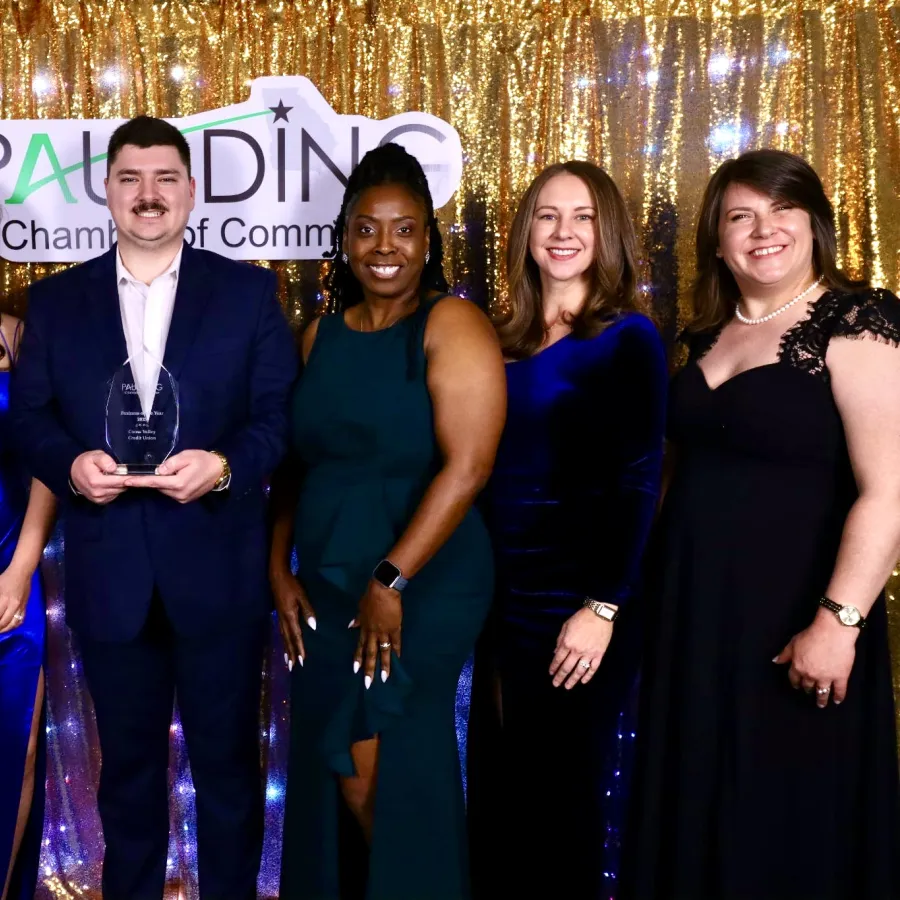 Group of six people dressed formally posing with award in front of gold sequin backdrop at Paulding Chamber event