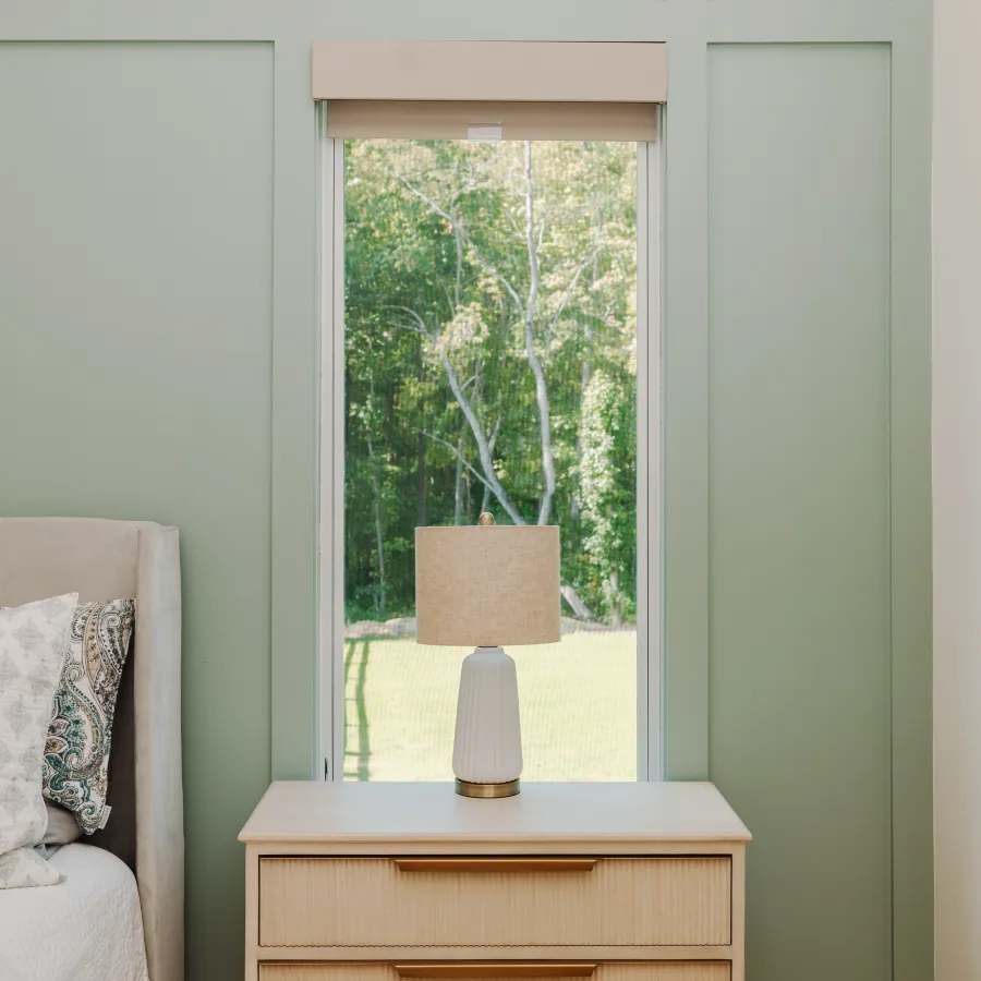 a room with a window and a lamp on a table in front of a casement window 