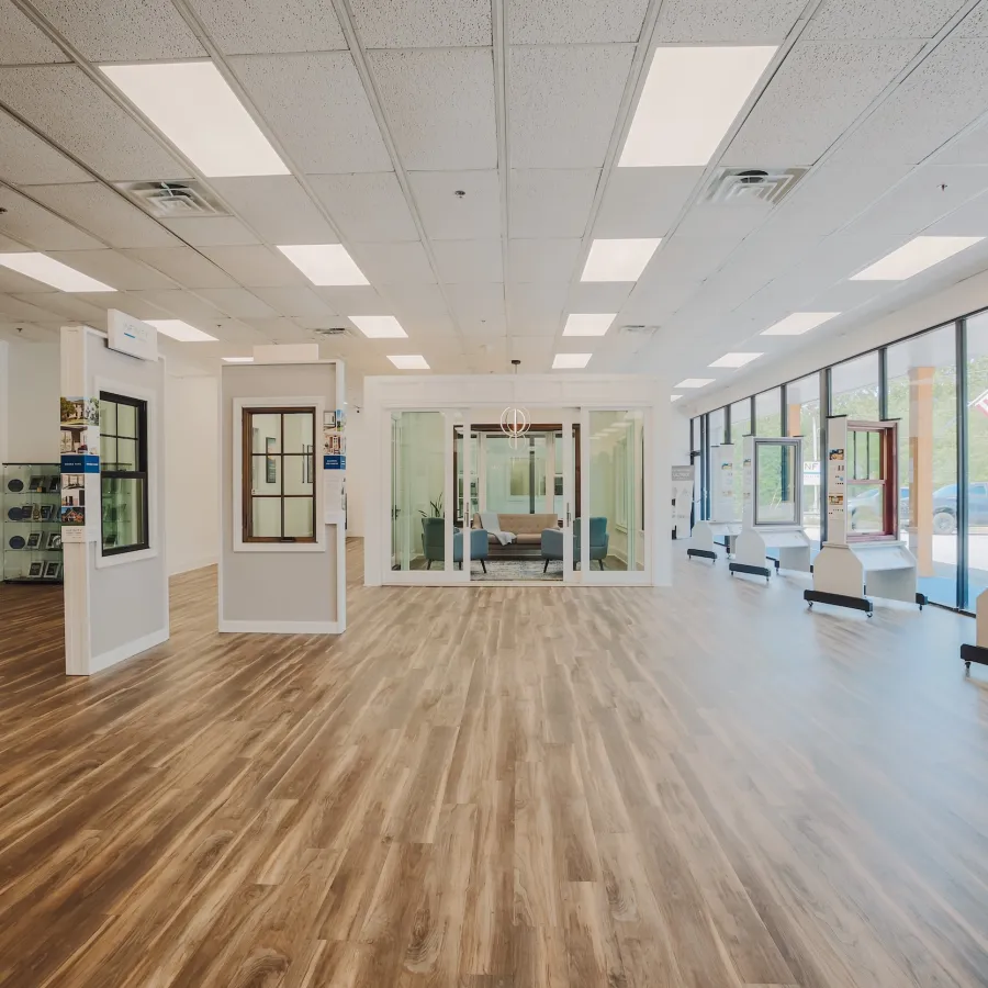 Bright spacious showroom with wood flooring displays windows and doors, large glass panels, and modern lighting.