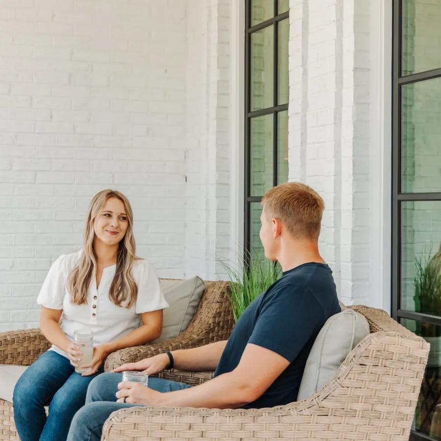 a man and woman sitting on a couch in front of black fiberglass windows with grids