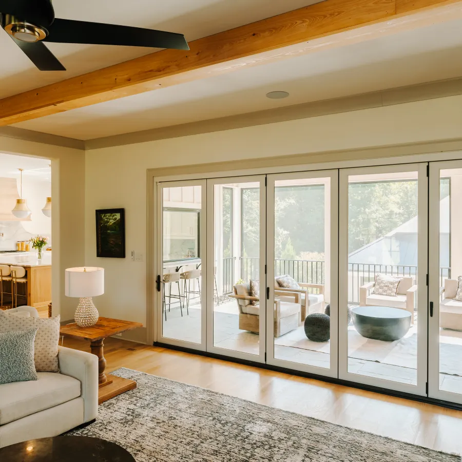 Modern living room with large sliding glass doors, soft furnishings, and natural light.