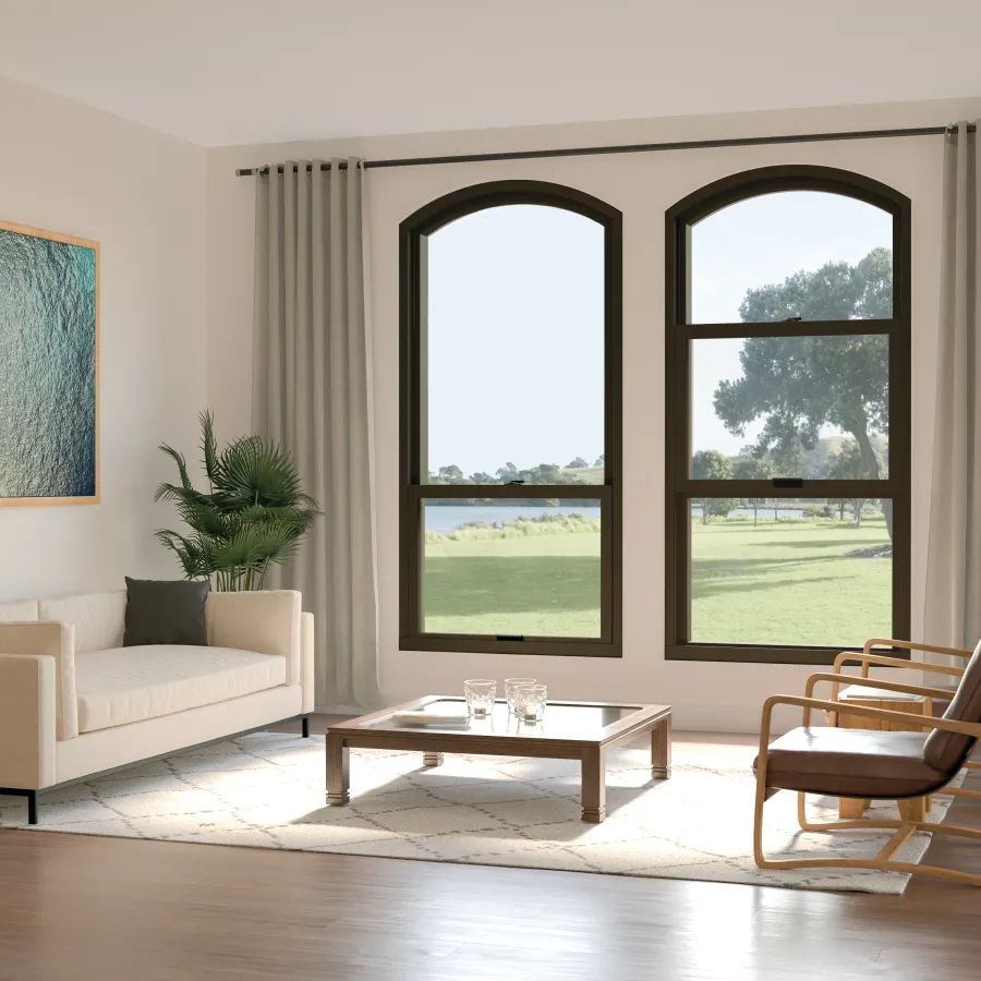 a living room with two large single hung round top windows overlooking a green space