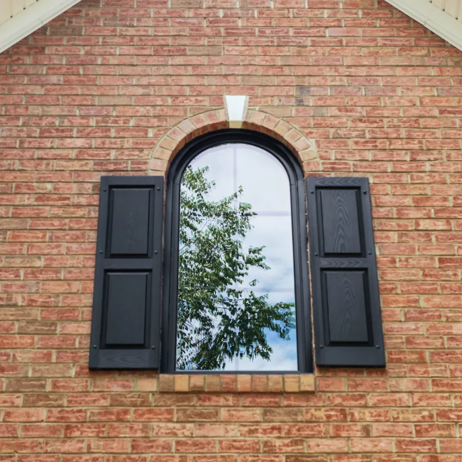 a brick building with round top window with shutters