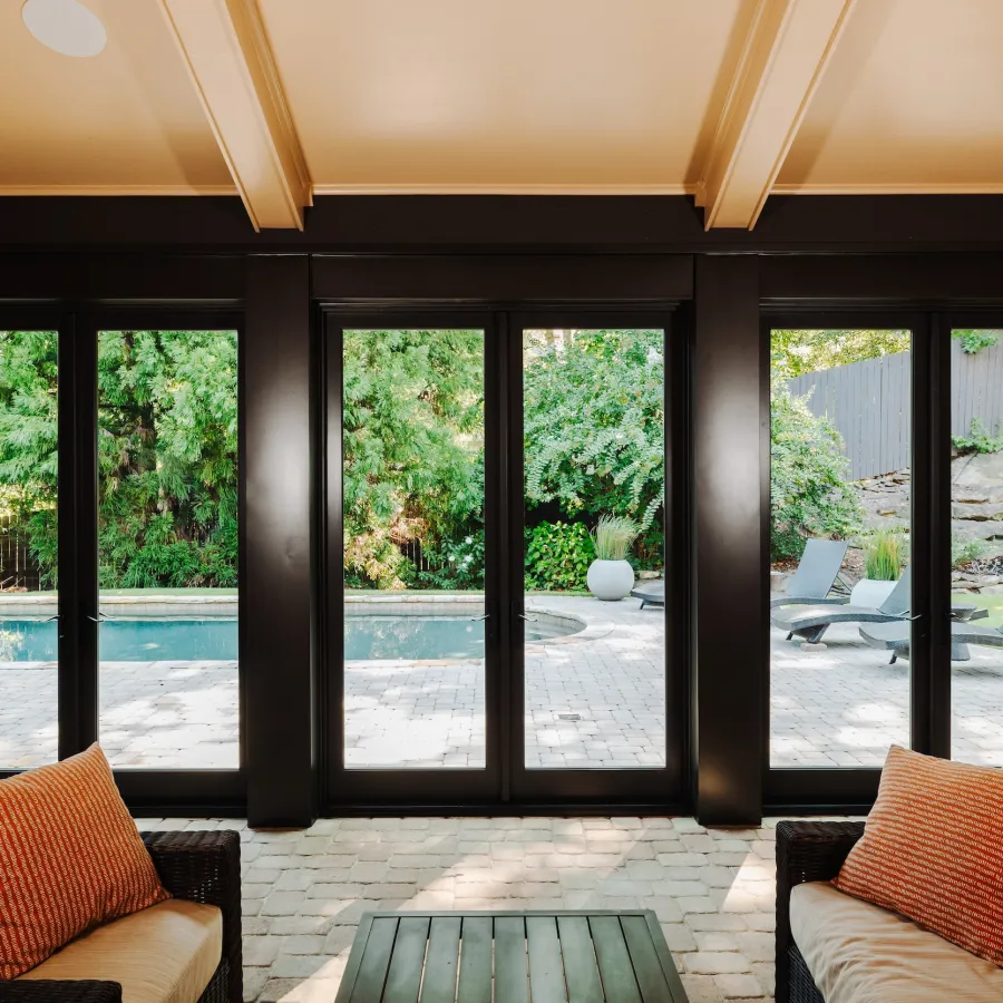 Enclosed patio with three black, outswing French doors leading to pool deck.
