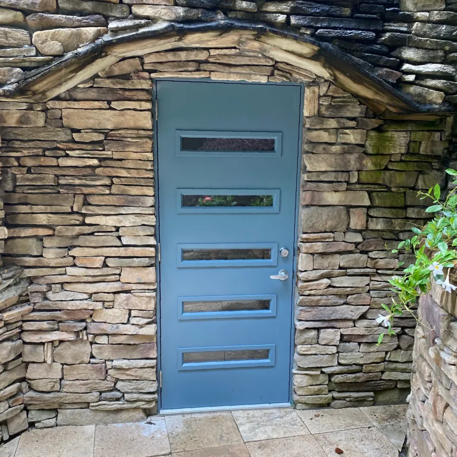 Modern blue door from ProVia on stone wall 