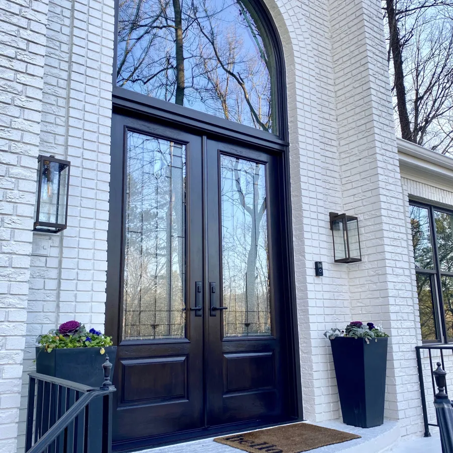 Black double front doors with decorative glass under an arched transom