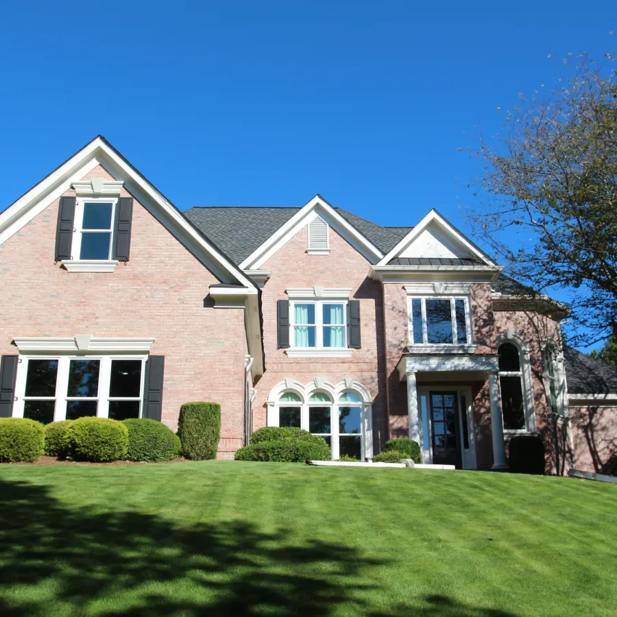 Large brick two-story house with white fiberglass double hung windows