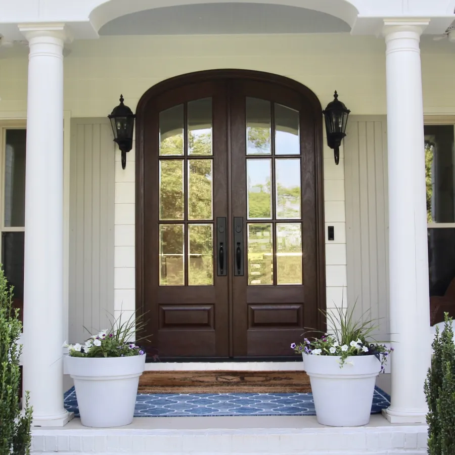 Double entry door stained in dark wood tone with glass on front porch