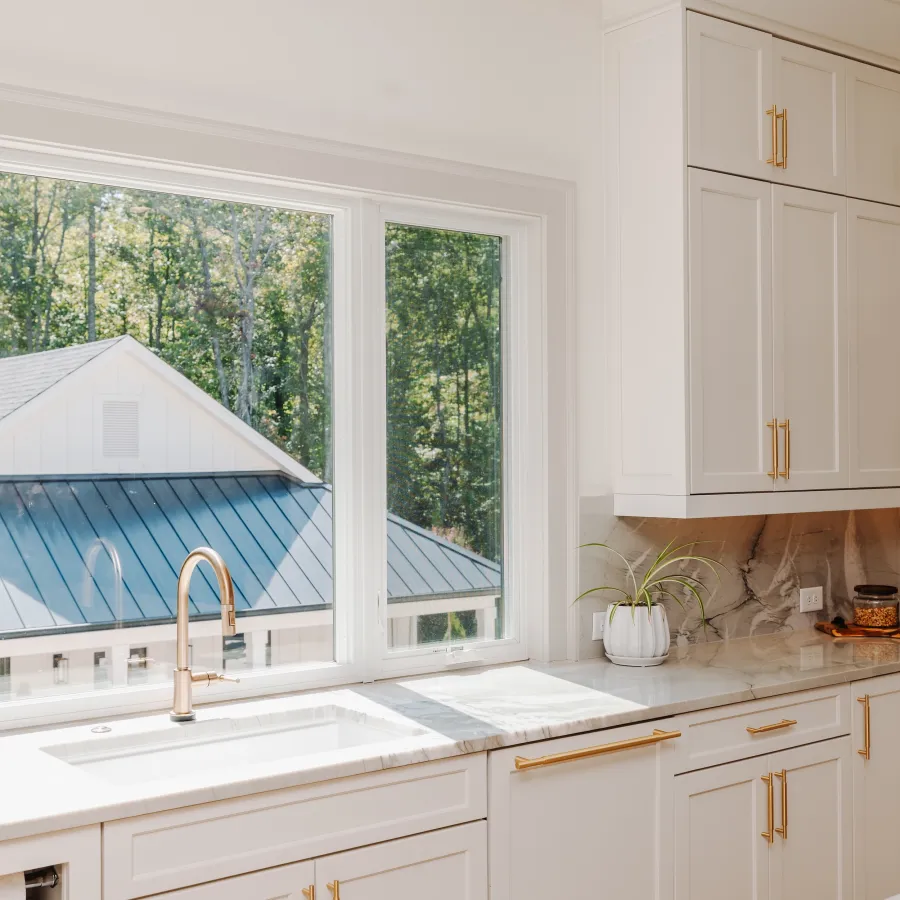 a kitchen with white cabinets and white casement windows above the sink