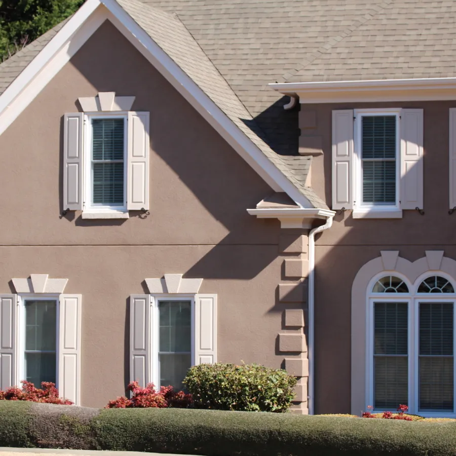 A brown house with cream shaker shutters
