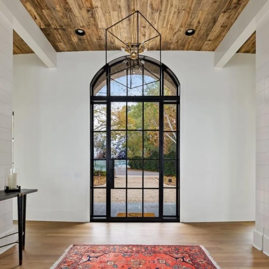 Interior of front entry with arched glass entry door with thin, modern iron frame