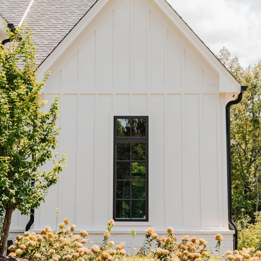 White board and batten house with black fiberglass casement windows with black grids. 