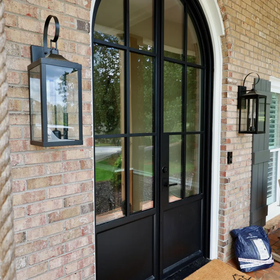 Black arched double front doors on brick house