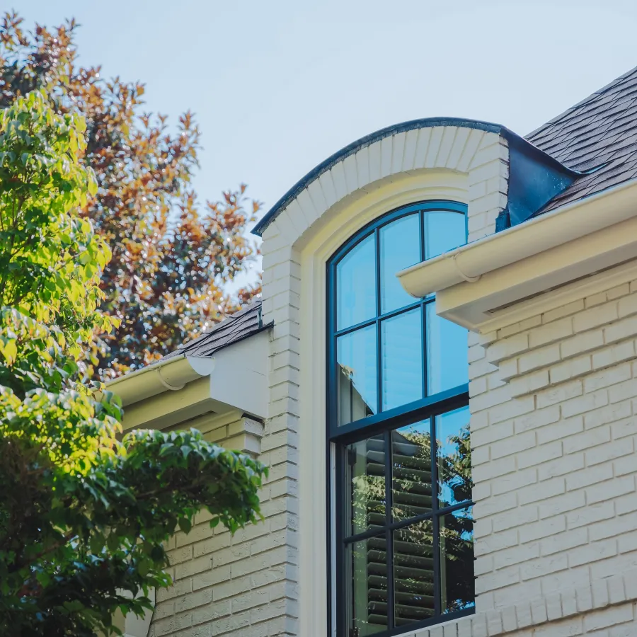 Black fiberglass double hung round top window installed on white brick house