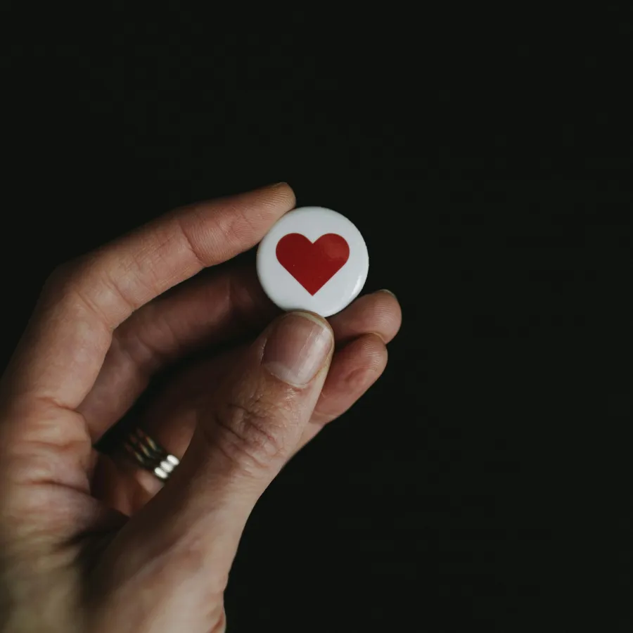 a hand holding a red and white heart