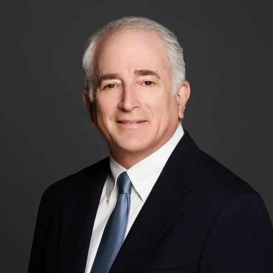 Portrait of a professional man in a suit with a neutral background, exuding confidence and approachability.