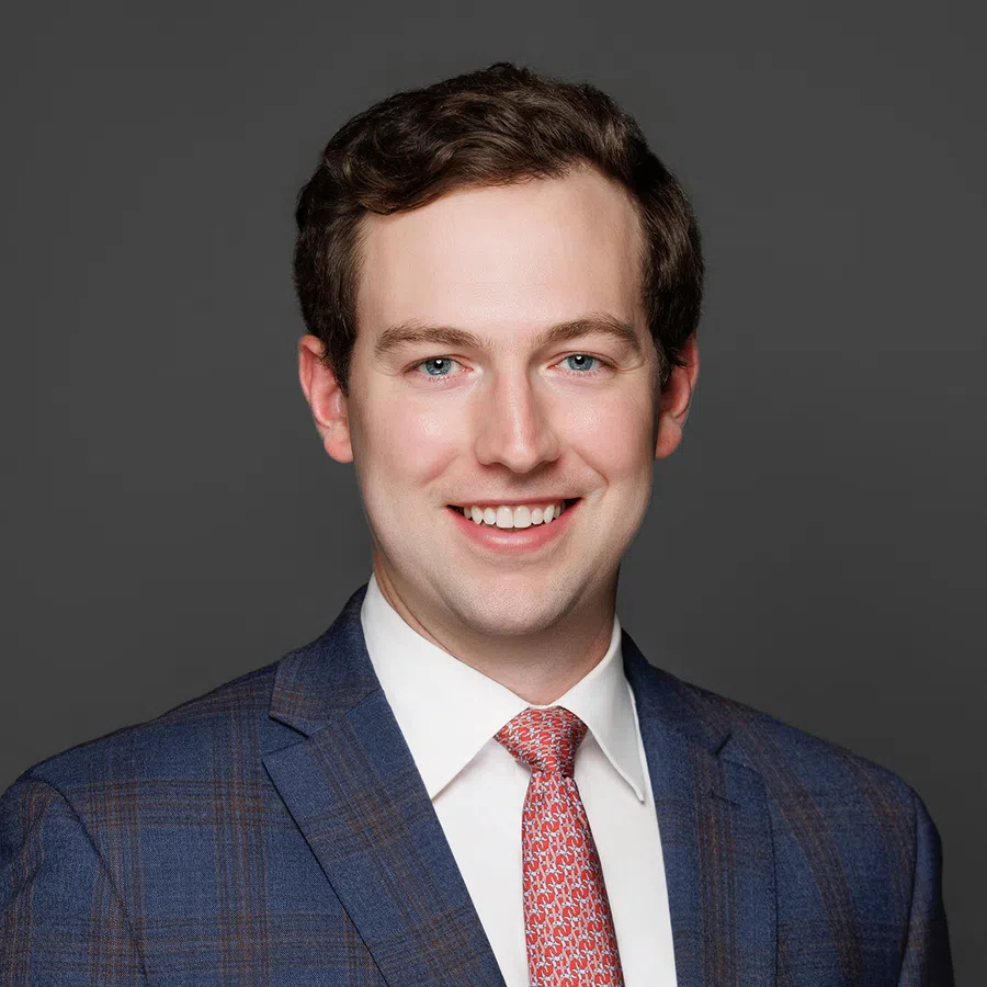 Smiling young man in a blue plaid suit jacket and red patterned tie on a gray background