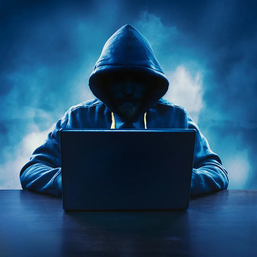 a person wearing a hoodie and using a laptop