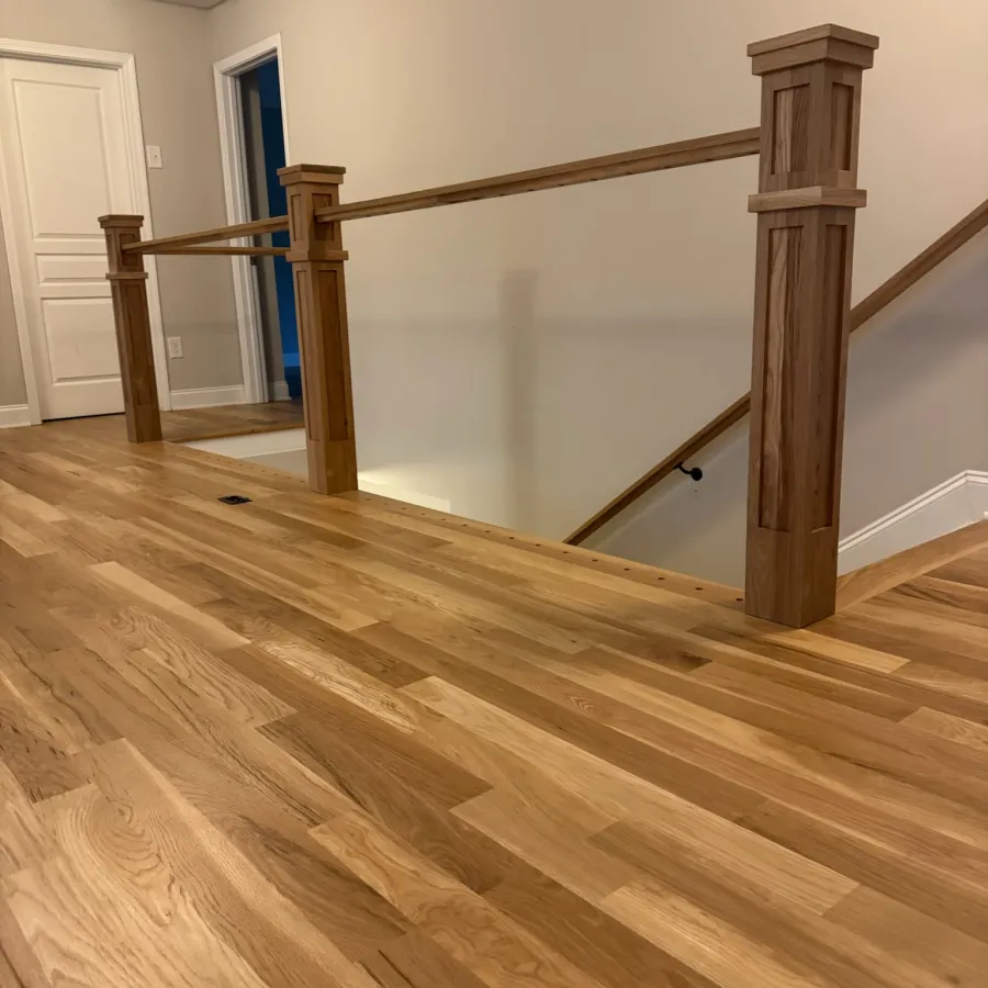 Interior view of wooden floor and wooden stair railing with beige walls and white doors indoors.