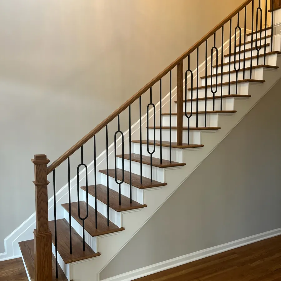 Wooden staircase with white risers and black metal railing in a modern home interior.