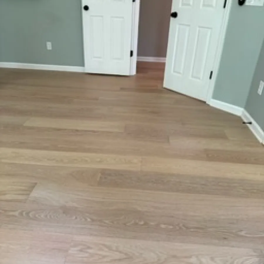 Room with light wood flooring, gray walls, white double doors, and a wall-mounted exercise bar.