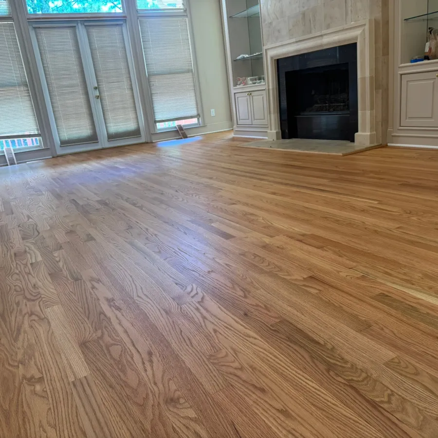 Spacious room with polished hardwood floors, large windows with blinds, and a fireplace with built-in cabinets.