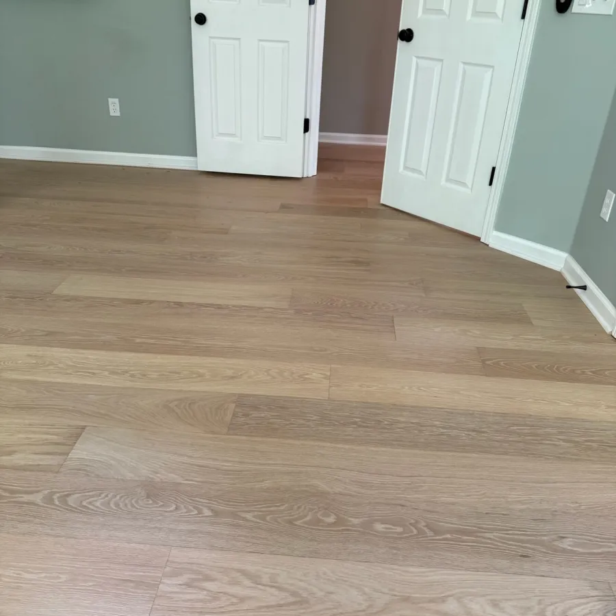 Room with light wood flooring, gray walls, white trim, and two white doors, one partially open.