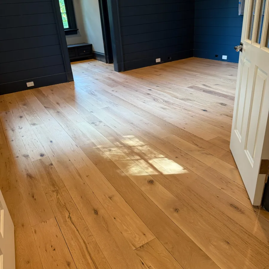 Spacious room with natural light on polished wooden plank flooring and dark navy walls.