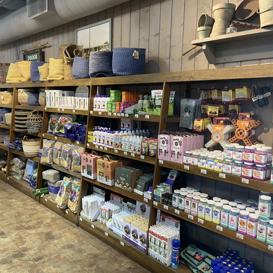 Wooden shelves in a store display woven baskets, gardening supplies, supplements, and health products against a wood-paneled wall.
