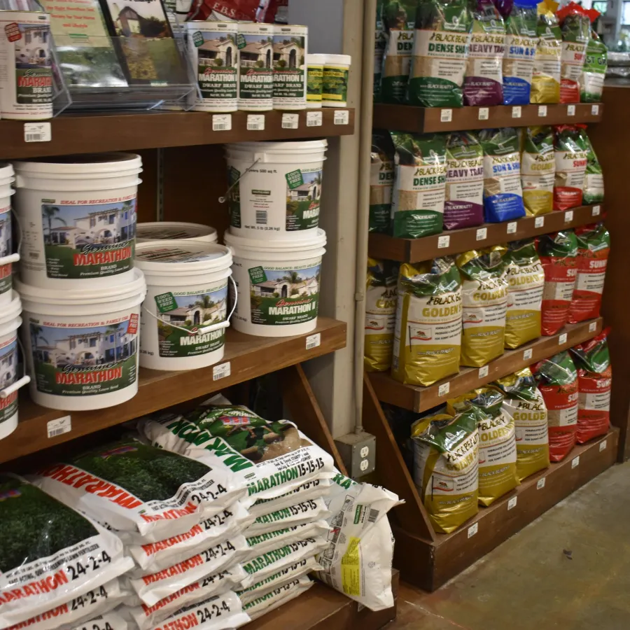 Store shelves stocked with various lawn care products including fertilizers and seed bags with colorful labels.