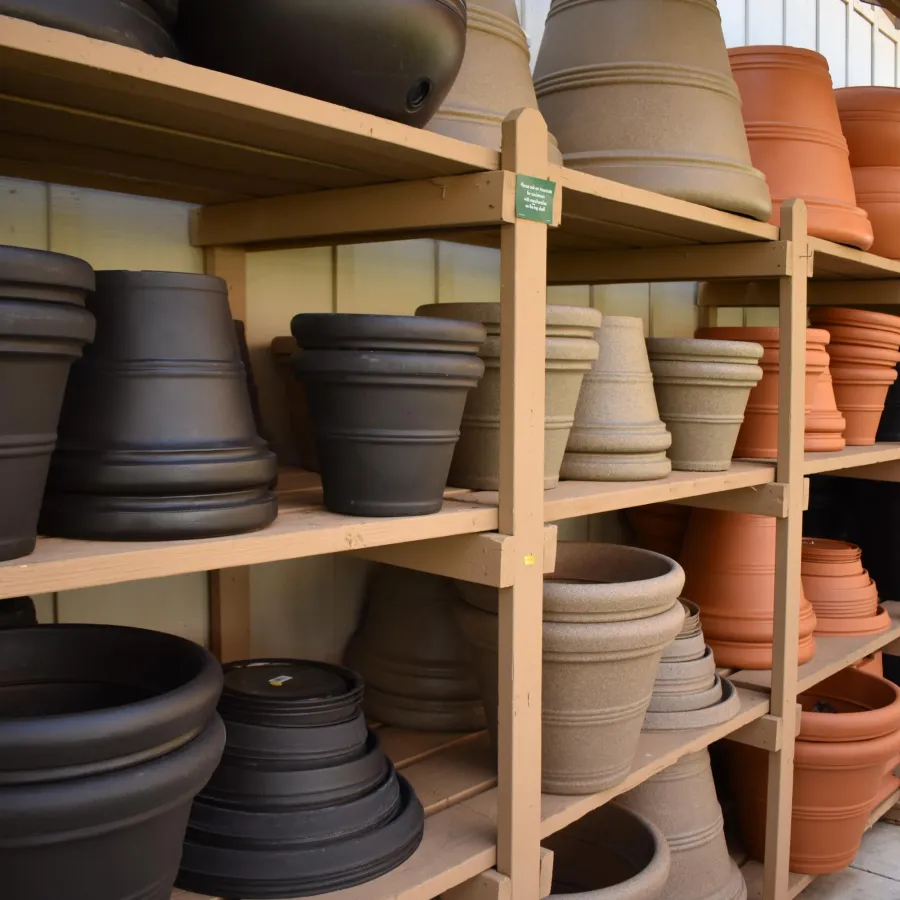 Shelves filled with various sizes and colors of empty plant pots in a garden center or store.