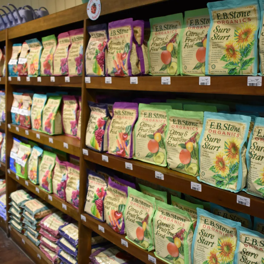 Shelves stocked with colorful E.B. Stone Organics gardening products including Sure Start and Citrus & Fruit Tree Food.