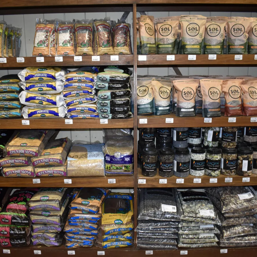 Shelves stocked with various gardening soils, fertilizers, and organic amendments in bags and containers.