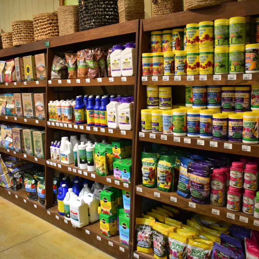 Shelves stocked with colorful gardening supplies including fertilizers, soil, and plant food in a garden store.