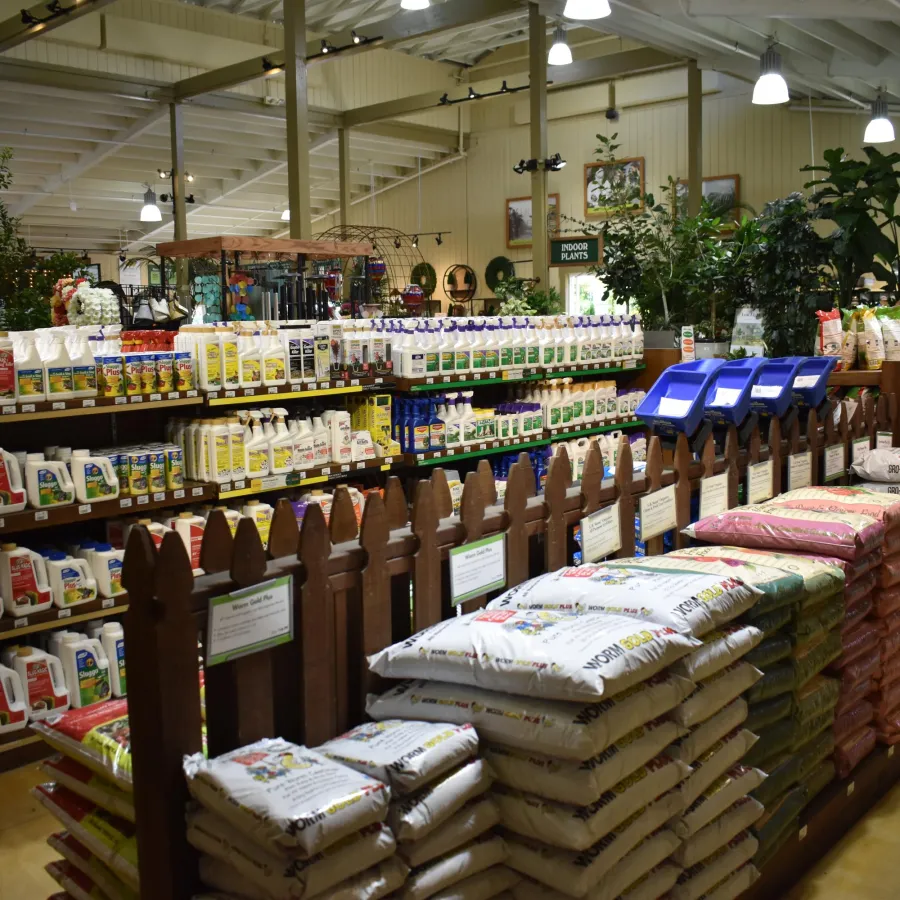 Indoor gardening section with shelves of plant care products and stacks of potting soil bags in a store.