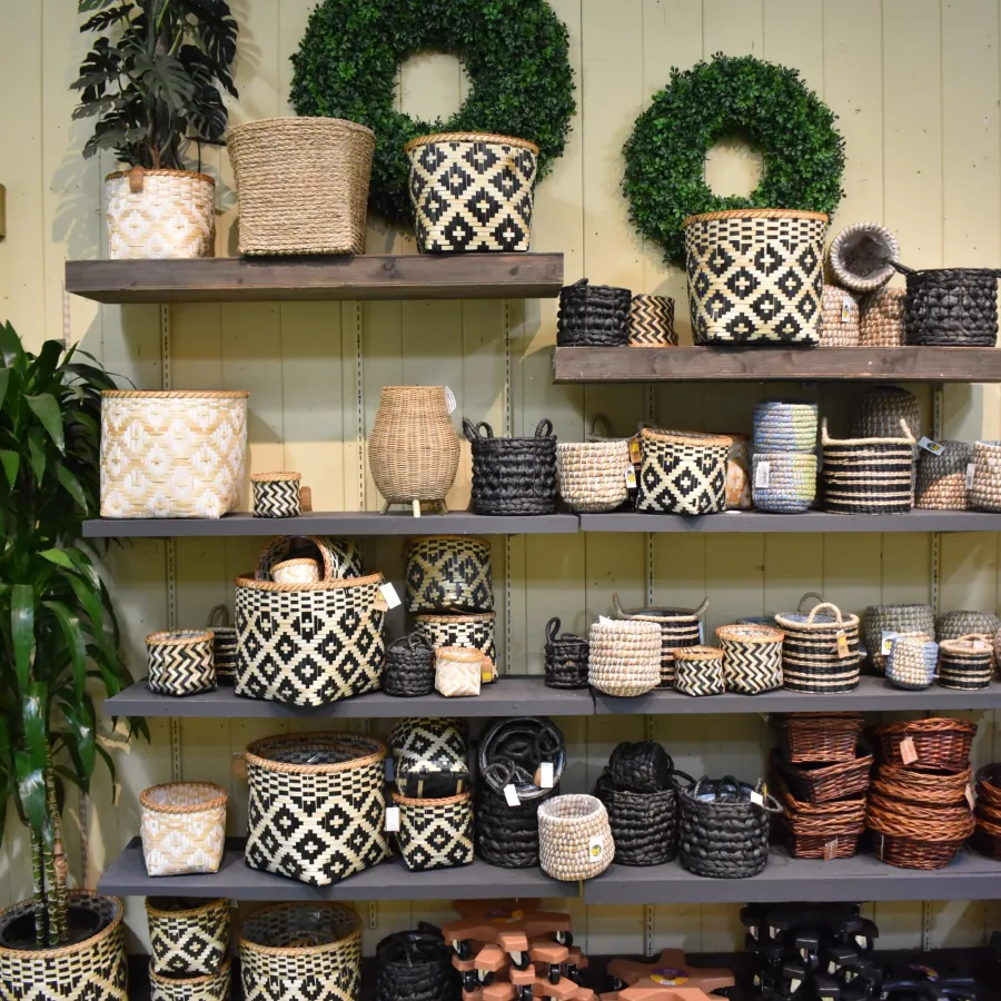 Shelves displaying various woven baskets and greenery wreaths in a retail store setting.