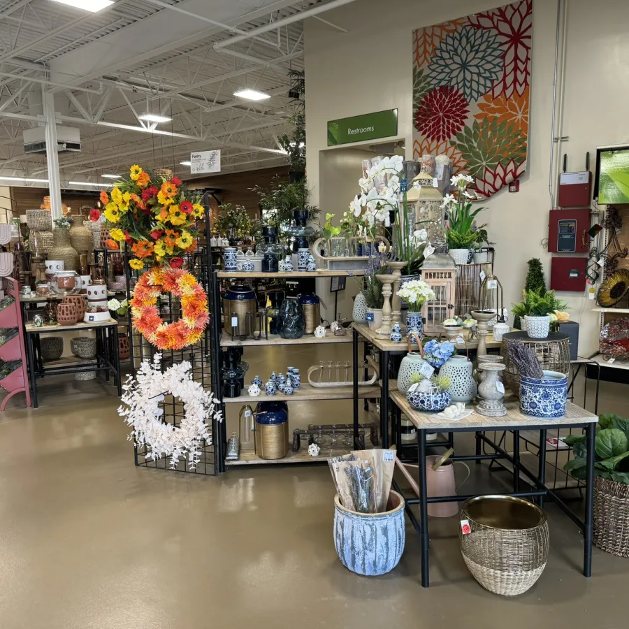 Indoor garden decor display with floral wreaths, ceramic pots, vases, and decorative plants in a store.