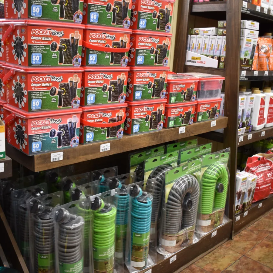 Shelves with assorted garden hoses and red package boxes of Pocket Hose displayed in a store.