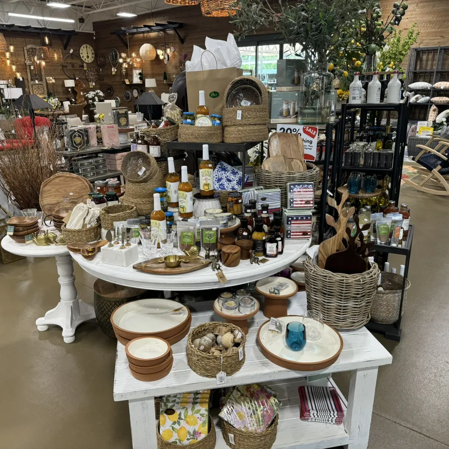 Display of artisanal kitchenware, woven baskets, glassware, and home decor items in a rustic store setting.