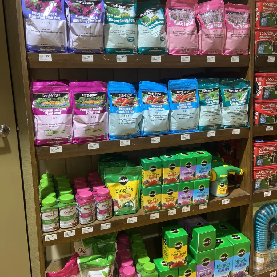 Shelves stocked with various plant foods and fertilizers in colorful packaging including Ferti-lome, Osmocote, and Miracle-Gro.