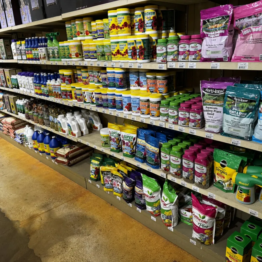 Store aisle stocked with various plant fertilizers, soil additives, and gardening supplies in colorful packaging.