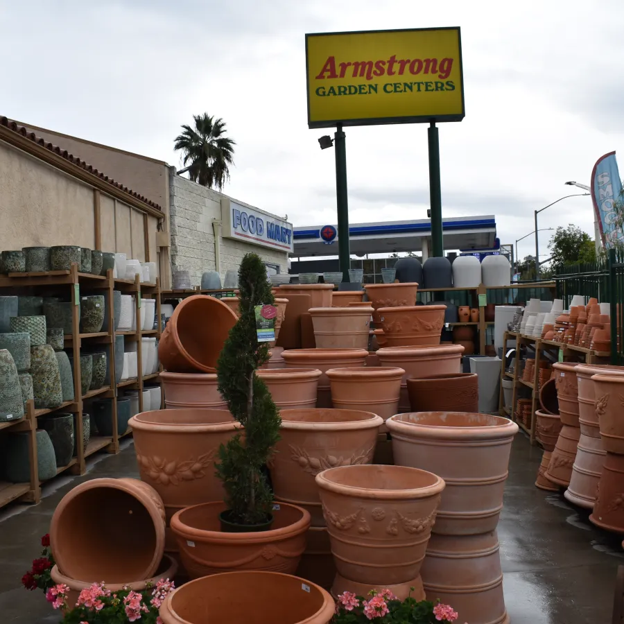 Outdoor display of various terracotta and ceramic pots at Armstrong Garden Centers with a clear store sign.